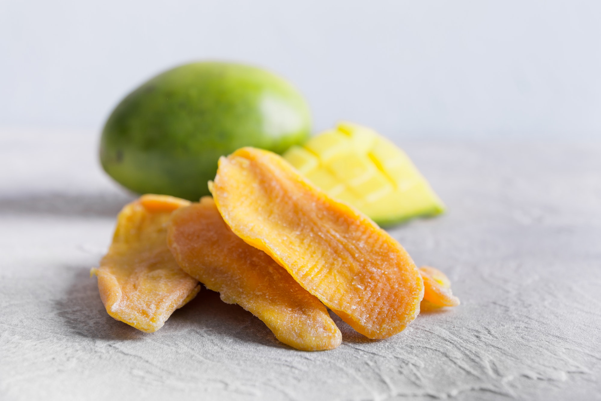 Dried mango chips on gray background. Close up.