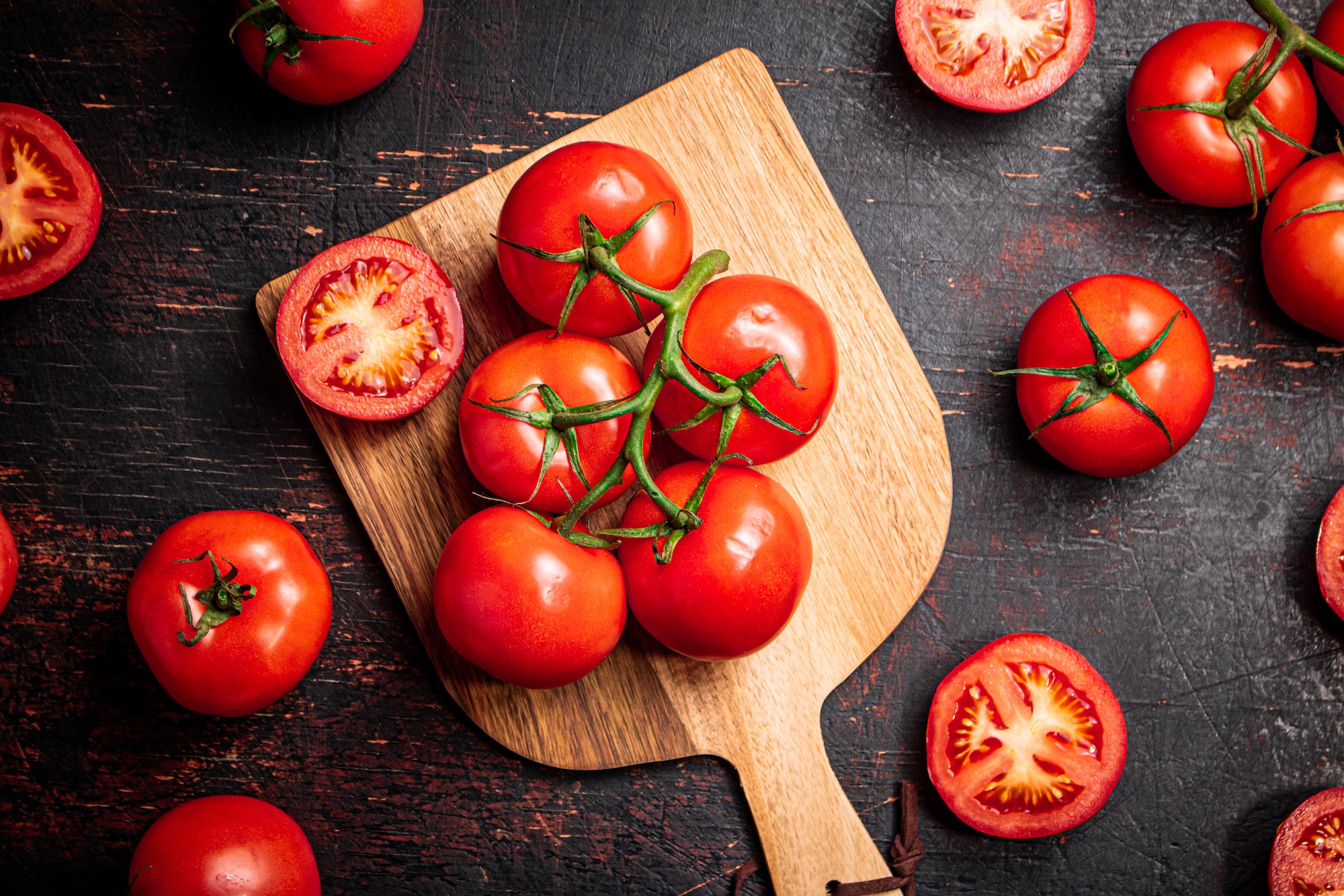 Fresh tomatoes on a wooden cutting board.